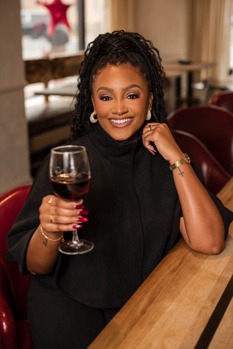 Cassandra, founder of Cork’d, seated at a wine bar holding a glass of red wine